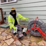 plumber feeding hose into pipe