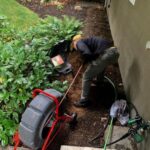 man working on plumbing outside house