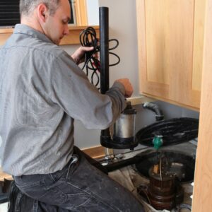 Plumber servicing a sump pump.