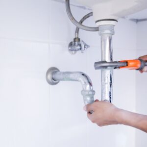 Plumber using a wrench to fix a drain