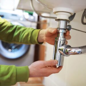 Close up of person fixing pipe under sink
