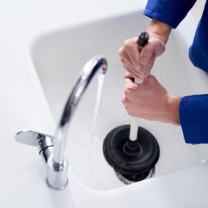 Person using a plunger on a running sink