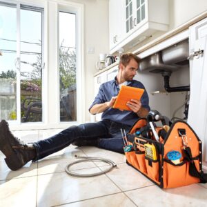 Plumber inspecting a clogged kitchen drain