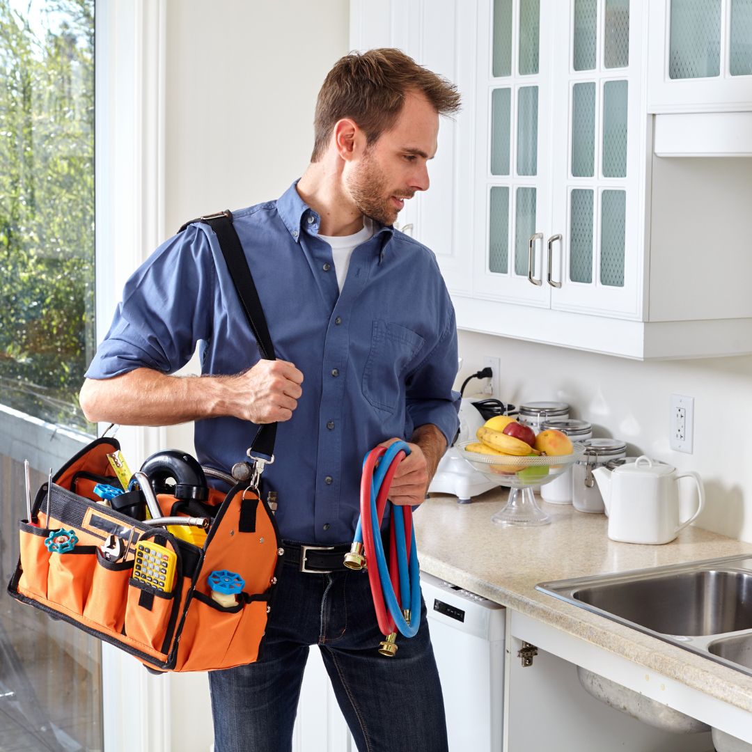 a plumber with tools looking at a kitchen sink