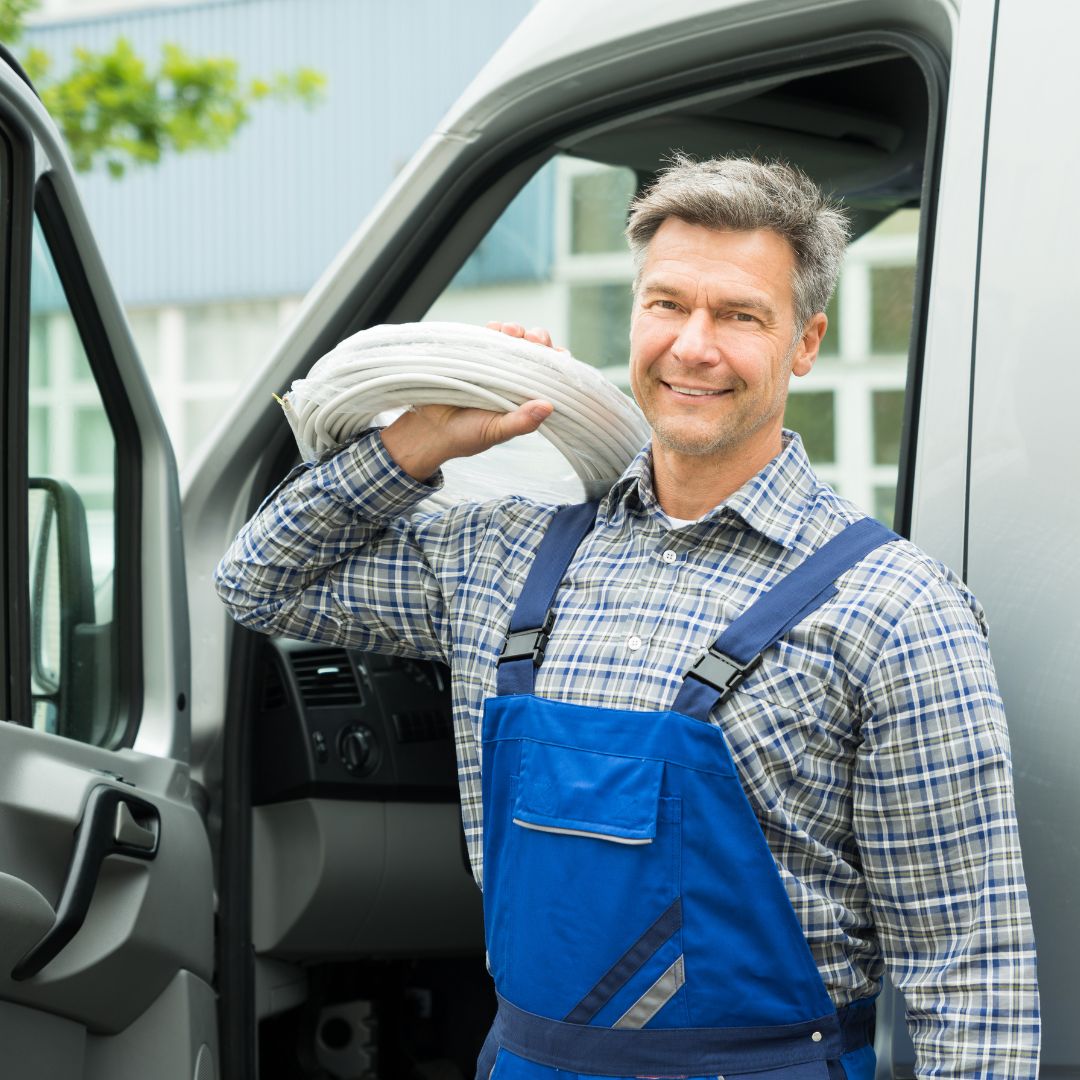a plumber carrying hoses out of a van